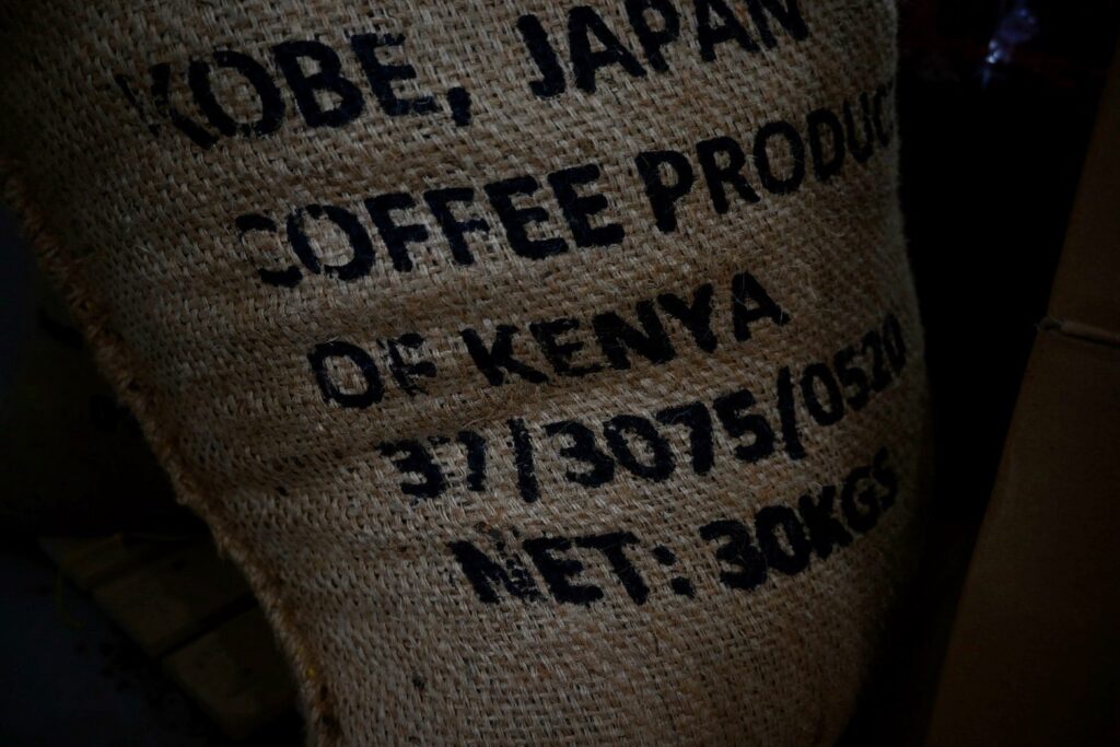 ケニア産のコーヒー生豆が入った麻袋。「COFFEE PRODUCT OF KENYA」「NET: 30KGS」などの文字が印刷されている。
