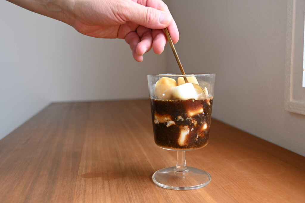 注ぎ終わったカフェオレベースと牛乳氷をスプーンで優しく混ぜ合わせる様子